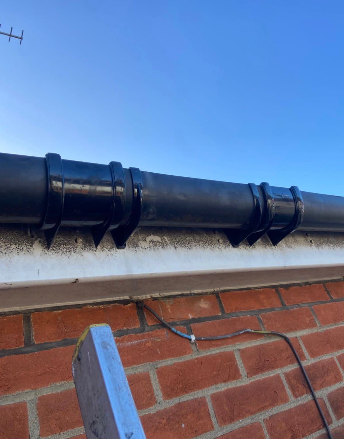 New black downpipe on a brick wall